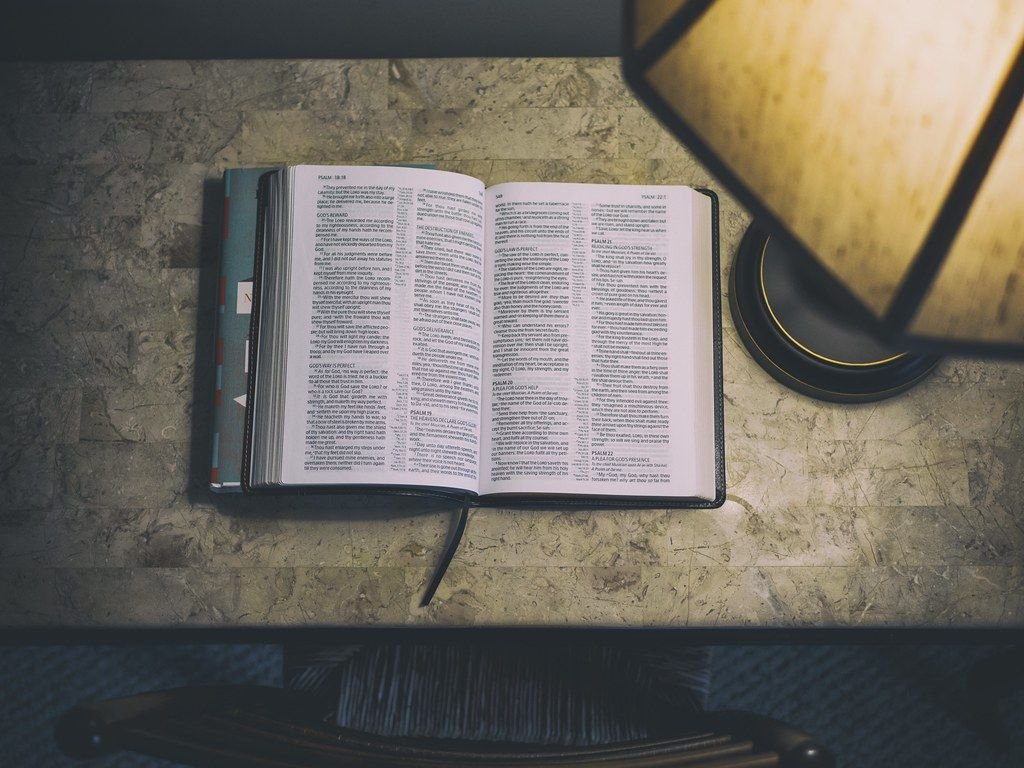 An open Bible on a desk beside a lamp – setting aside three days of fasting to seek God through His Word and prayer
