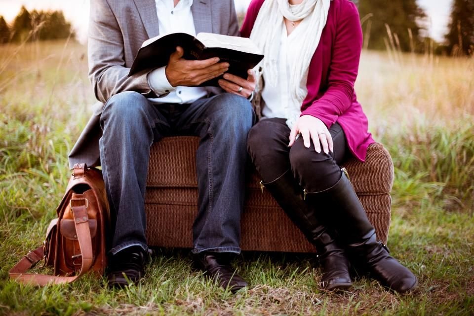 Christian couple sitting together outdoors reading the Bible – praying for a healthy marriage after deliverance