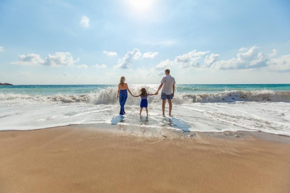 Family holding hands walking toward the ocean at sunrise – hope for a peaceful home and children