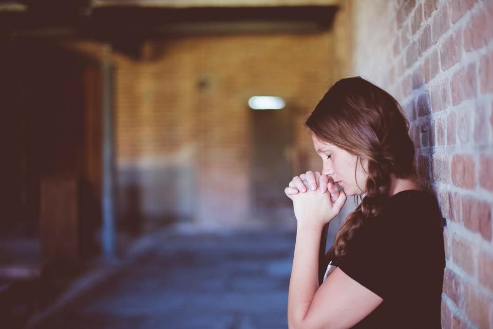Young woman praying quietly with folded hands – fasting for deliverance and prayer