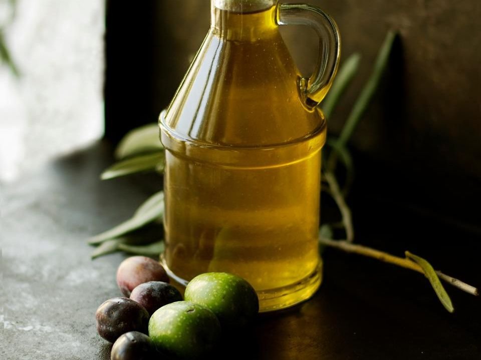 Glass bottle of olive oil with fresh olives – how to anoint your room with oil