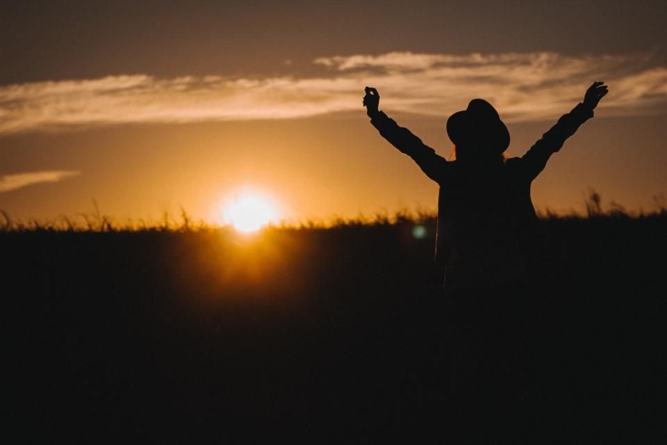 A person raising both arms toward the setting sun – the freedom believers seek when they learn how to pray for deliverance