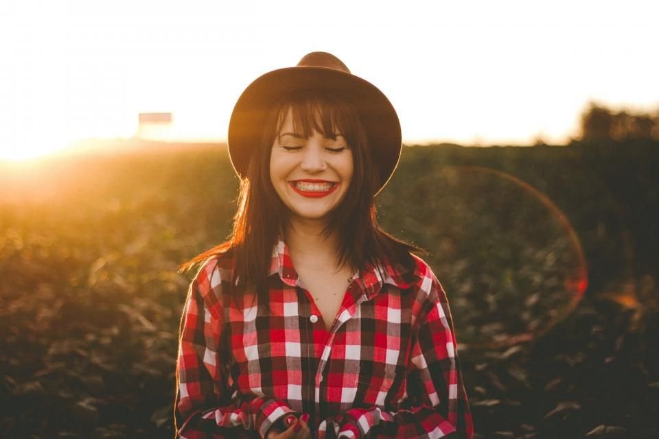 A smiling young woman standing in warm evening sunlight – waiting on God with joy and hope