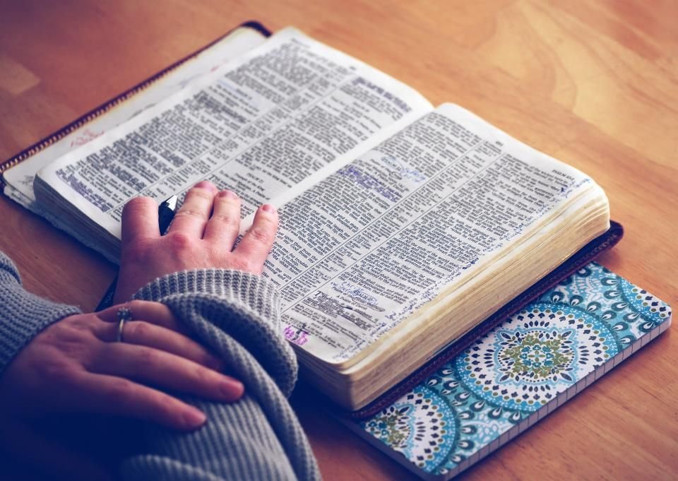 Hands resting on an open Bible – reading Scripture for marine spirit meaning