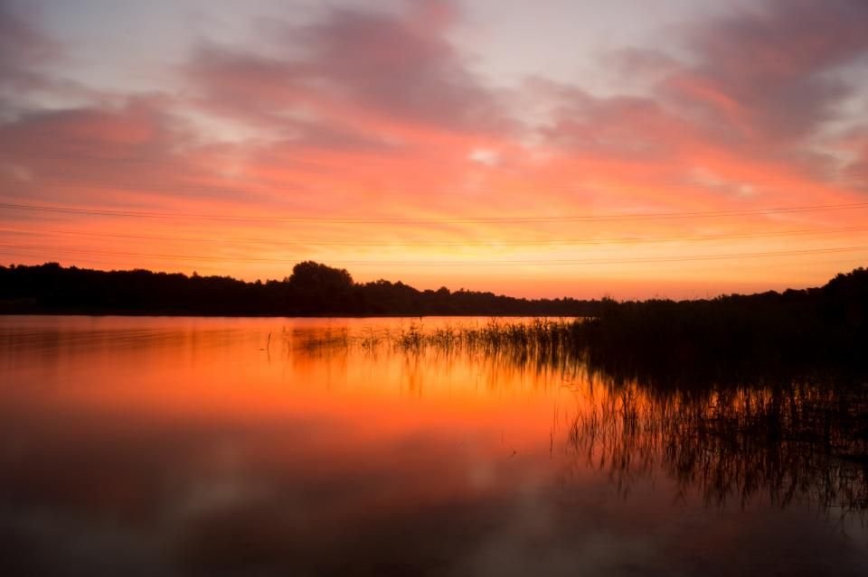 Orange sunrise over still water and reeds – a new morning of peace after prayer