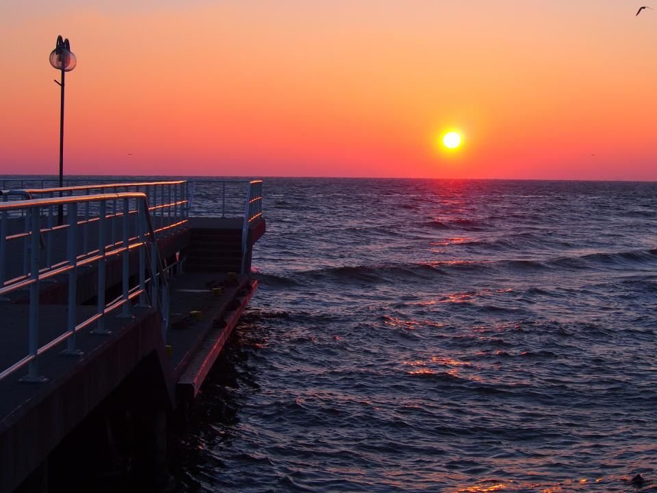 Golden sun rising over a calm sea beside a pier – God’s peace after prayer