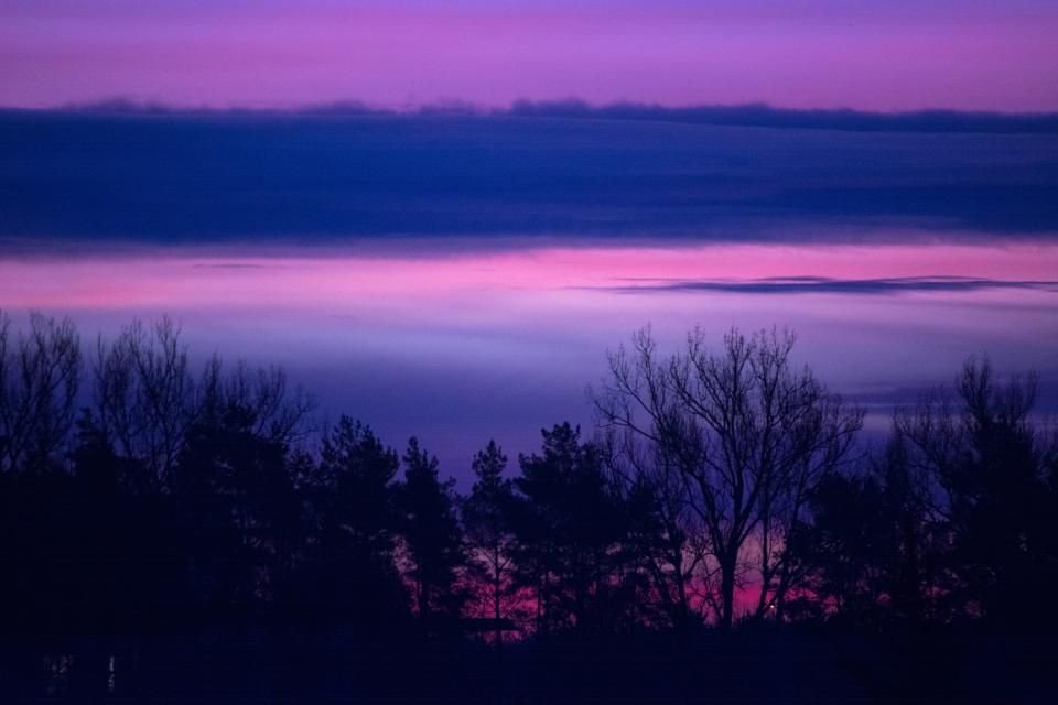 Purple dawn breaking over a dark forest – night gives way to morning, and God keeps watch through every hour