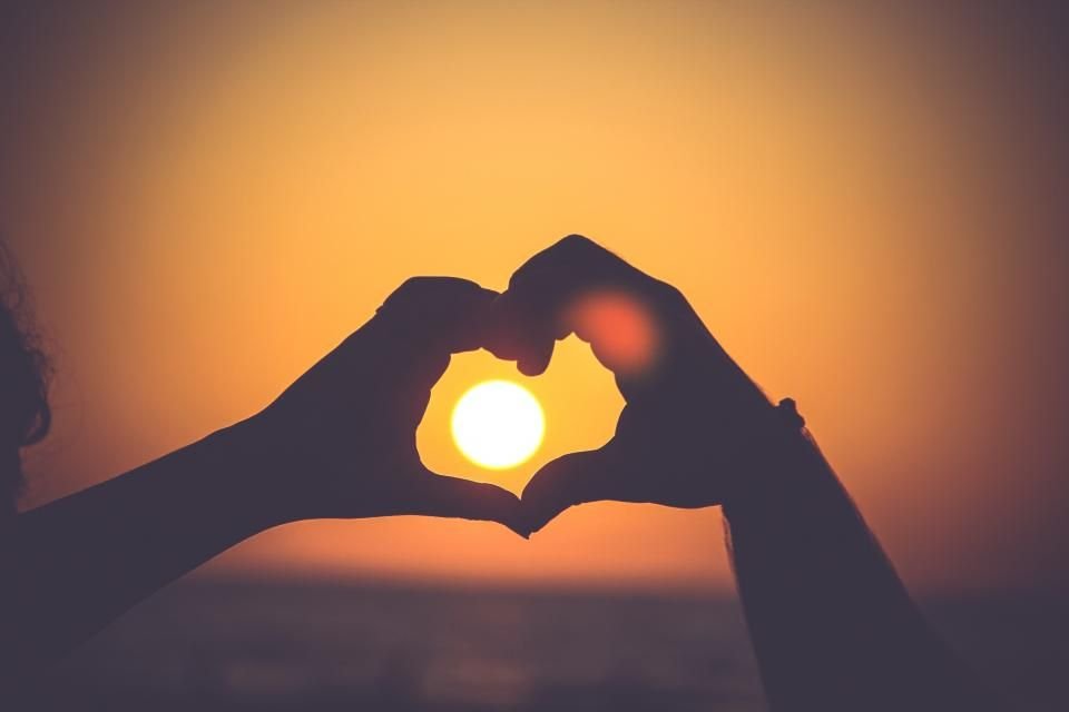 Hands forming a heart around the setting sun – God's love answers the pain of rejection