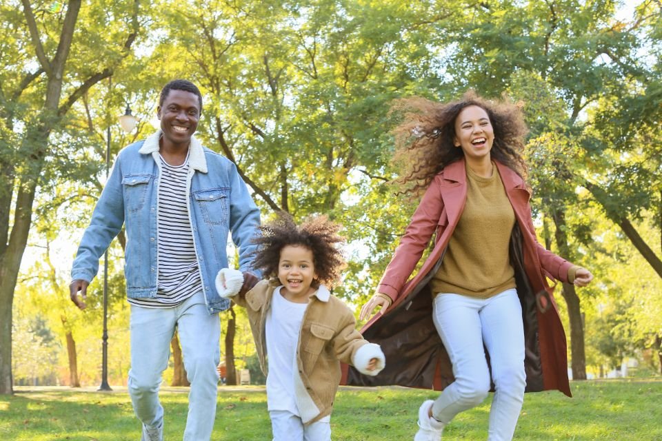 A smiling African family running together in a sunny park – praying for long life over your family