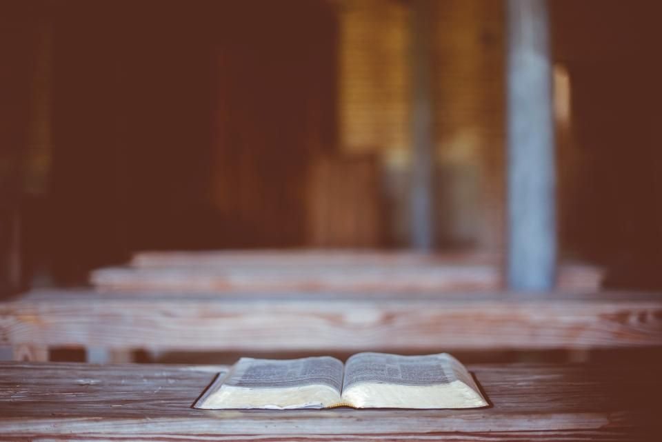 Open Bible resting on a wooden church pew in warm light – a quiet place for prayer against witchcraft