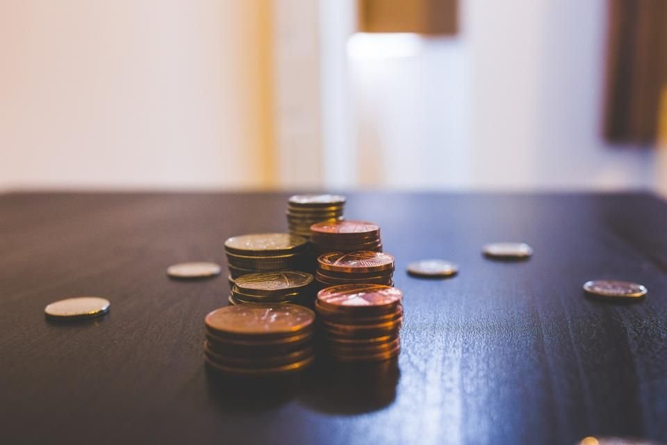 Small stacks of coins on a wooden table in soft light – praying for financial breakthrough and God's provision