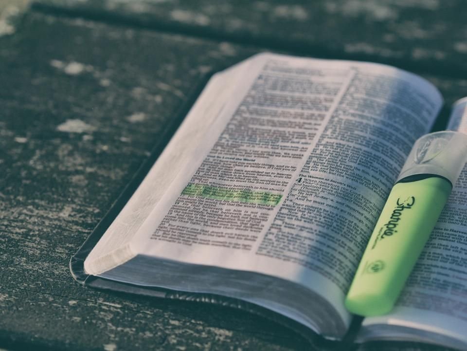 An open Bible with a highlighted verse and a marker on a wooden table – praying Psalm 91 for protection