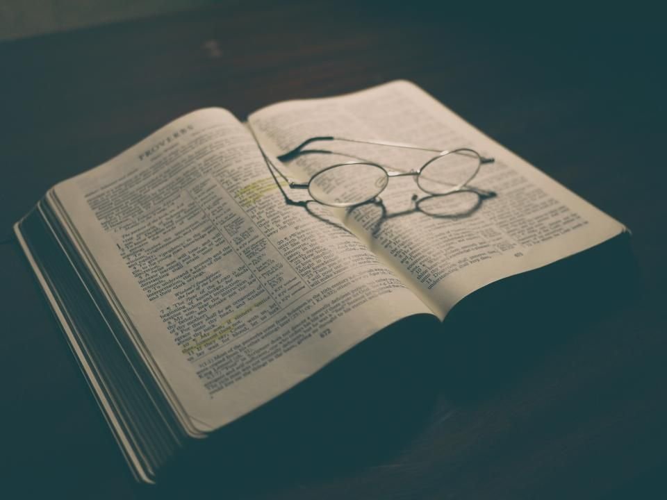 Open Bible with reading glasses in a dim room – praying a psalm prayer for protection at night