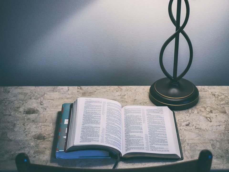 Open Bible beside a glowing bedside lamp – reading psalms for protection at night before sleep