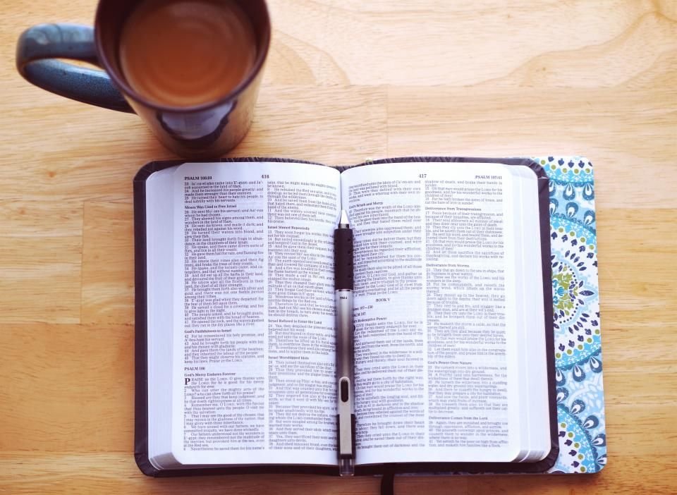 Open Bible with a pen and a cup of tea on a wooden table – studying scriptures for marriage breakthrough